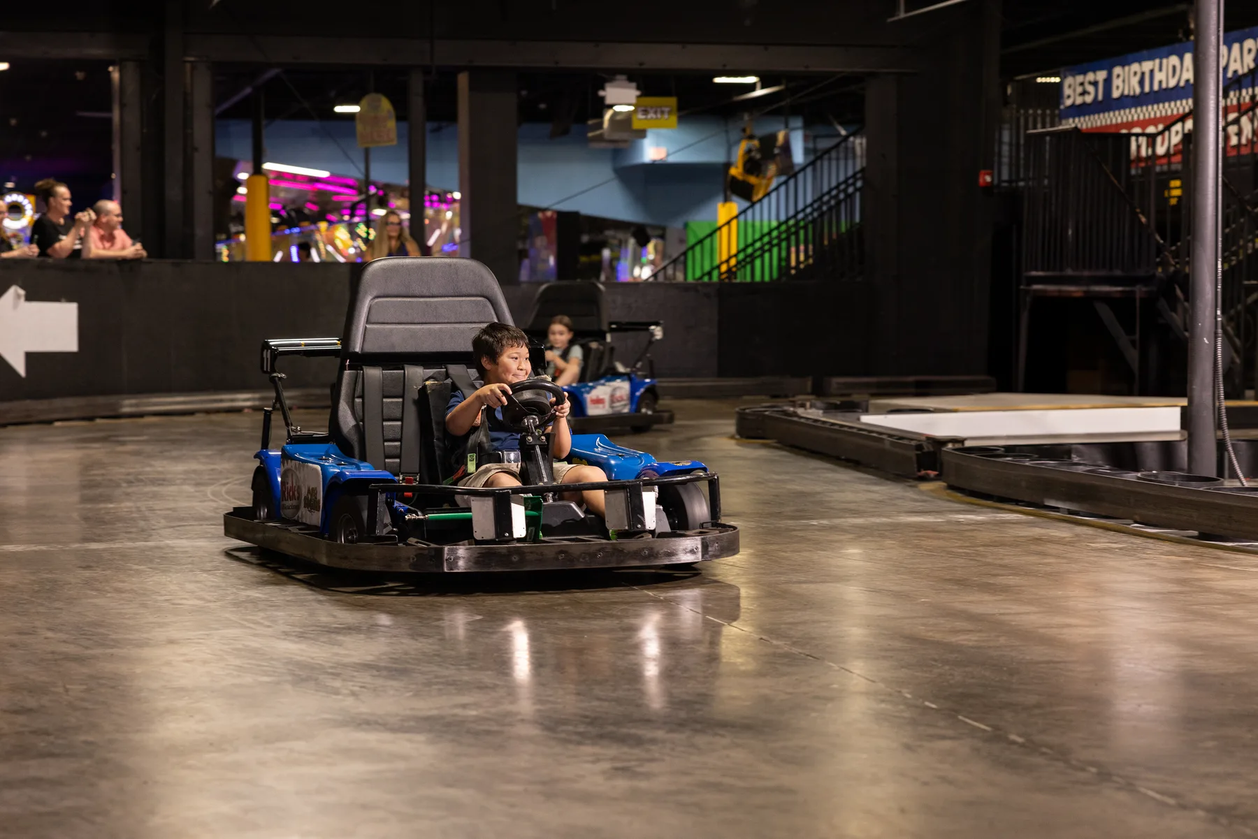 A child driving a go-kart inside an Incredible Pizza attraction area