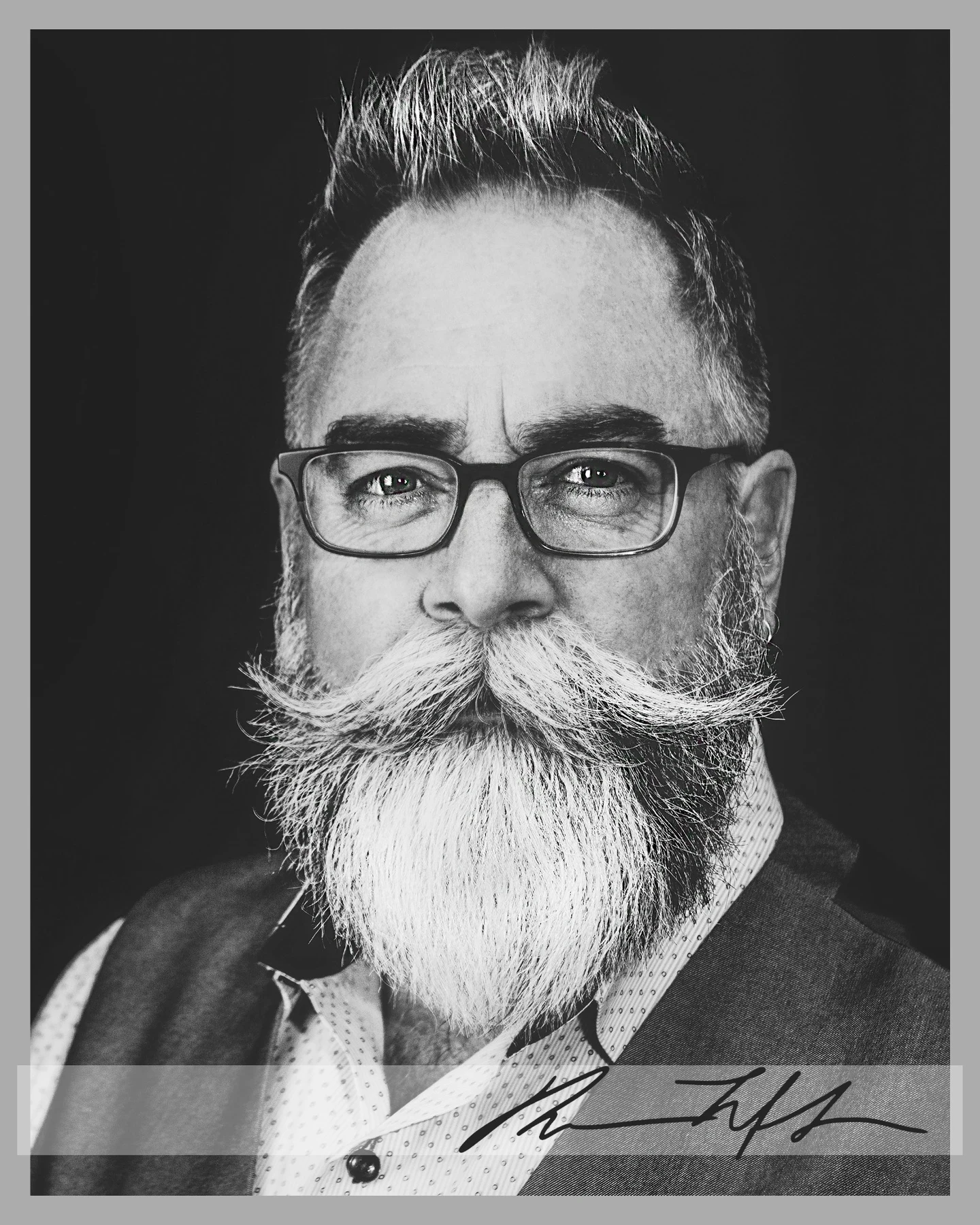 High-contrast black-and-white character portrait of a bearded subject wearing glasses