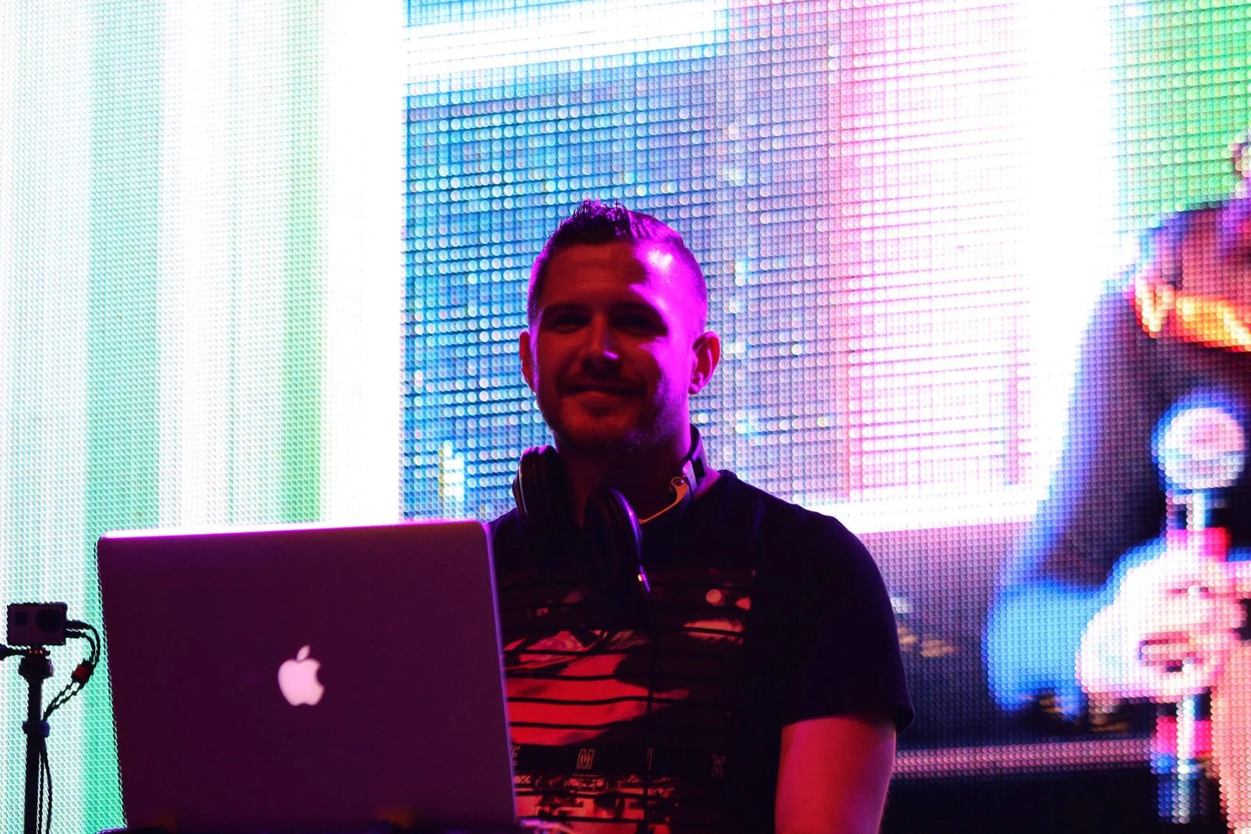 TIFFIN performing a DJ set behind a laptop with a colorful LED wall