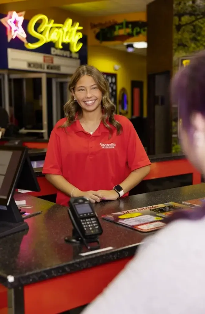 Frontline team member at Incredible Food & Fun greeting a guest, illustrating that strong standards can stay consistent while human judgment keeps the experience personal.